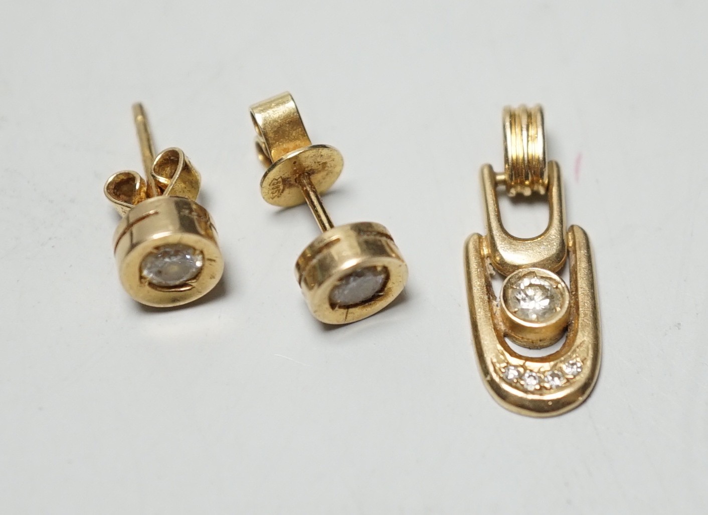 A modern pair of 585 yellow metal and solitaire diamond set ear studs, 6mm and a matching pendant, gross weight 3.9 grams.